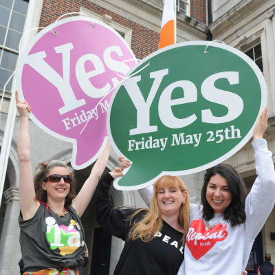 Tre kvinnor håller upp plakat för att fira att ja-sidan segrade i den irländska folkomröstningen om abortlagar i maj 2018. 