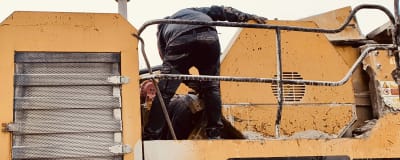En maskin som används i samband med husrivningar har gått sönder och arbetarna försöker reparera den.