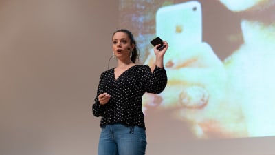 Felicia Margineanu håller en telefon i handeln framför en bild på Monalisa.