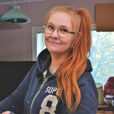 Björk lér och tittar in i kameran framför sitt förråd med restaurerade möbler.