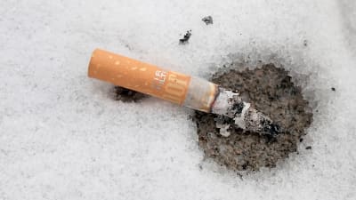 En brinnande cigarrettfimp som slängts i snön. 