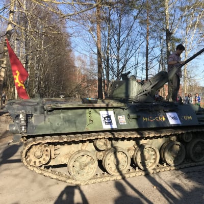 En pansarvagn med en röd flagga och en studerande på.