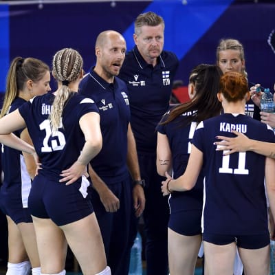 Volleybolldamerna samlade runt sin tränare.