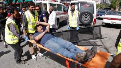 En skadad man bärs iväg på bår efter självmordsattacker i Afghanistans huvudstad Kabul. 