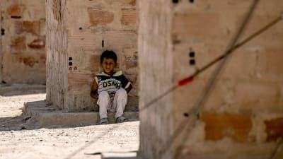 En liten pojke sitter i skuggan inne i lägret al-Hol 2.6.2019.