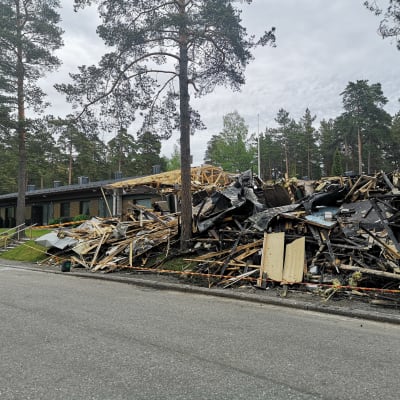 En bild på en radhuslänga som har brunnit ner. I bakgrunden syns ett grannhus som överlevt branden.