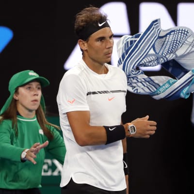 Rafael Nadal slänger sin handduk över axeln åt en bollpojke.