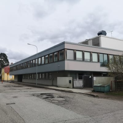 En stor vit byggnad vid en asfalterad gata.