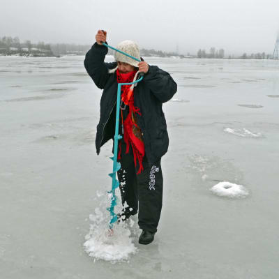Sari Snellman borrar upp ett hål i isen.