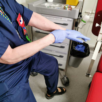 Sairaanhoitaja laittaa suojakäsineitä käsiinsä Tampereen yliopistollisessa sairaalassa