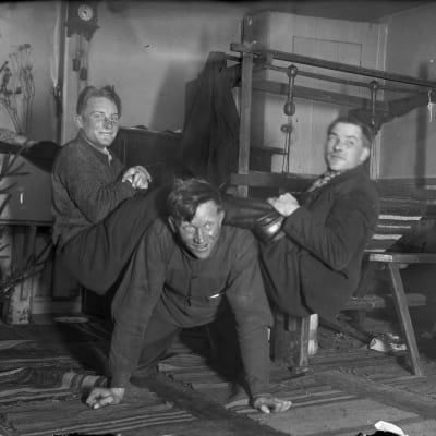 Tre män leker "lyfta saltsäck", där en person är på golvet på alla fyra, och två andra är på den förstas rygg medan han försöker stiga upp. Bilden är tagen 1935 i Bromarf.