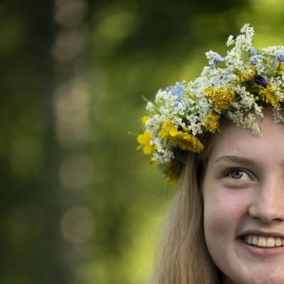 En glad flicka med en blomsterkrans i håret.