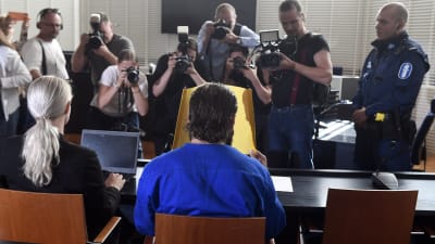 Den yngre brodern täckte sitt ansikte inför pressfotograferna.