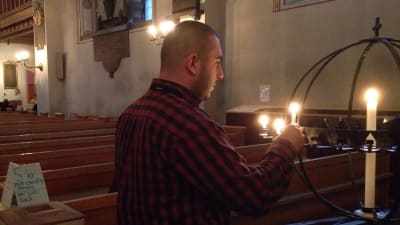Den intervjuade asylsökanden tänder ett ljus i kyrkan.