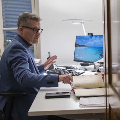 En man sitter och jobbar vid sitt skrivbord och kollar i sin kalender.