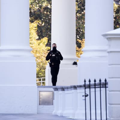 Yhdysvaltain salaisen palvelun univormuihin sonnustautuneen joukon jäsen vartioimassa Valkoista taloa.