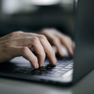 Närbild av händer spm skriver på en dator, laptop.