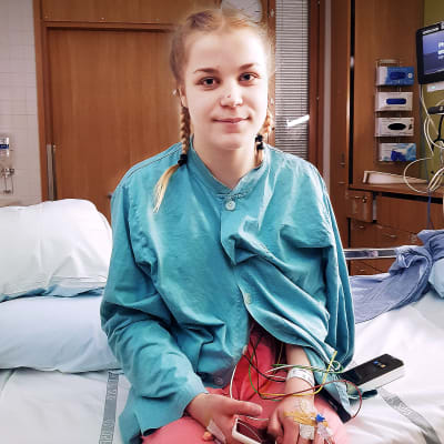 Anni Lamminsivu istuu sairaalan sängyllä leikkauksen jälkeen.