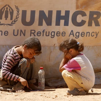 Två barn framför UNHCR:s banderoll.