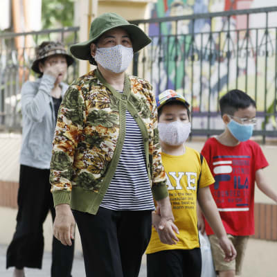 Kvinnor och barn på promenad i Hanoi på söndagen - alla utrustade med munskydd. 