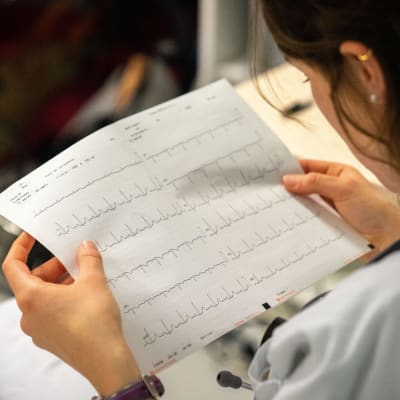 En sjukskötare eller läkare avläser ett EKG på papper.