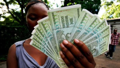 Kvinna i Zimbabwe håller upp nya sedlar med valören 10 triljoner i januari 2017. En triljon är det samma som en miljard miljarder.