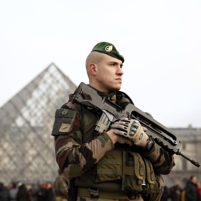 Soldat med maskingevär vaktar folkmassorna utanför konstmuseet Louvren i Paris.