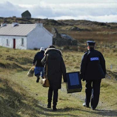 Polis och valförrättare bär på valurnan från ön Innishfree utanför Donegal. Två personer röstade.
