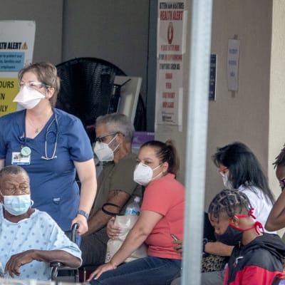 Folk i Florida väntar på att få komma in på ett sjukhus. Alla bär ansiktsskydd.