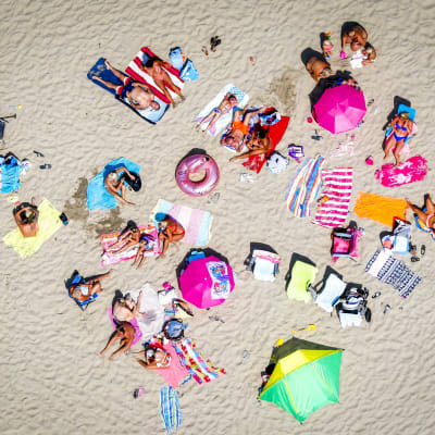Bild tagen ovanifrån på människor som ligger på en sandstrand.