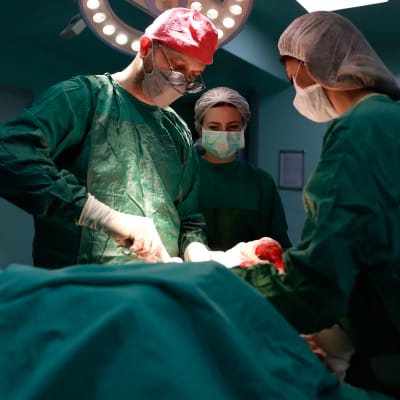 Två sjukskötare och en kirurg i en operationssal.