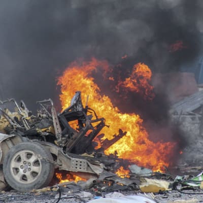 En bil brinner efter en explosion utanför hotell i Mogadishu.