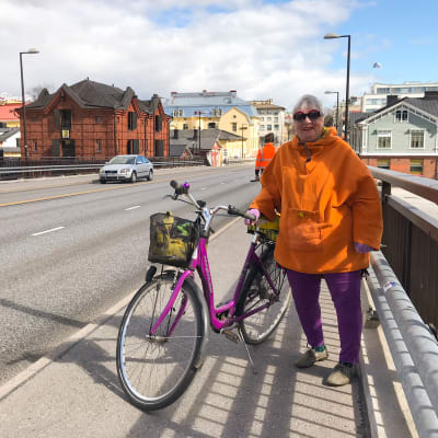 En kvinna med sin cykel på Mannerheimgatans bro.