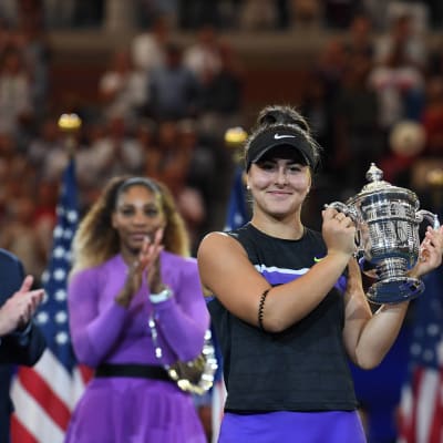 Bianca Andreescu poseeraa mestaruuspystin kanssa, Serena Williams taustalla.