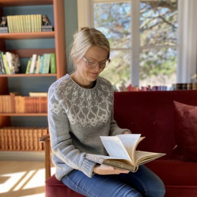 Anna Påfs-Streng sitter och tittar i en bok i Strömsös bibliotek.