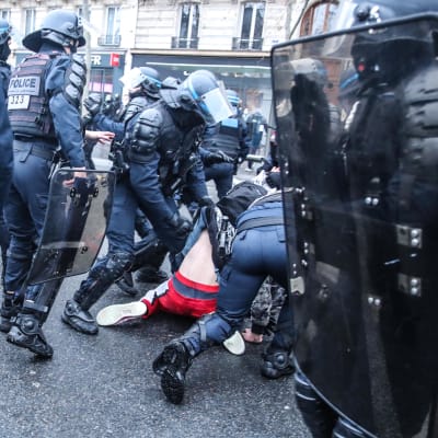 Polis samlade runt en demonstrant i Paris som ligger på marken.