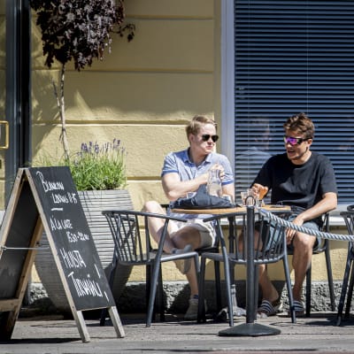 Flera personer sitter på en uteservering en solig sommardag.