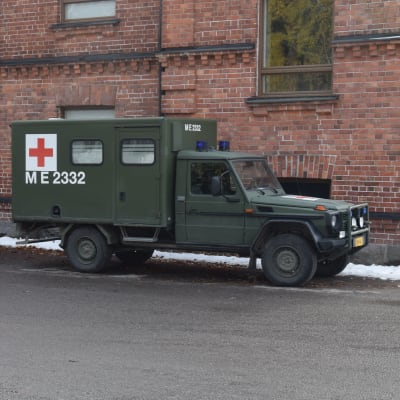 Två militärfordon utanför en kasernbyggnad.