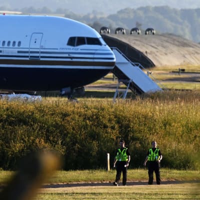 Kaksi huomioliiveihin pukeutunutta henkilöä kävelee lentokoneen edestä.