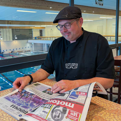 Rasmus Svahn sitter vid ett bord och läser tidningen.