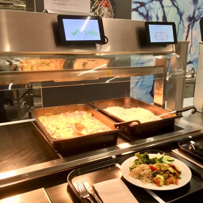 Varmrättsbord på restaurang med skärmar som registrerar matvalet. 