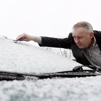 Man skrapar bort snö från bilens vindruta den 25.4.2017.