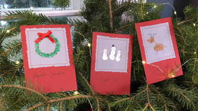 Tre handgjorda julkort i granris med ljusslinga.
