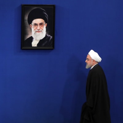 Irans president Hassan Rouhani går förbi ett foto på den högsta ledaren Ali Khamenei
