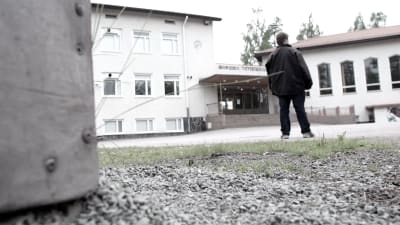 En människa står på en skolgård. Bilden har svaga färger. 