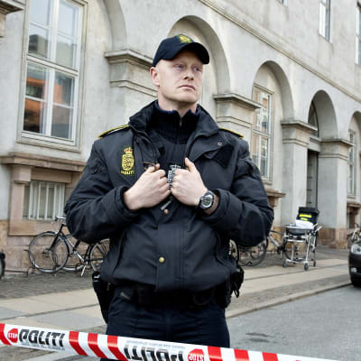 En ensam dansk polis står vid avspärrningsband på tom gata i Köpenhamn.