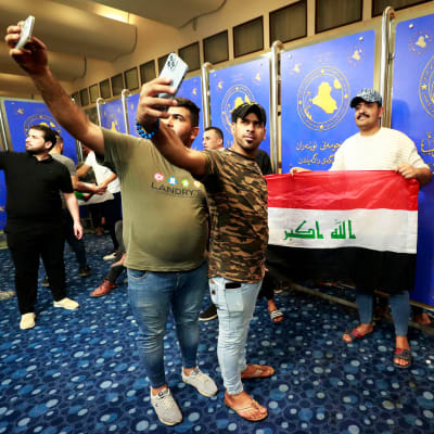 Ihmiset valokuvaavat puhelimillaan Irakin parlamentissa.
