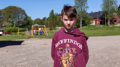 En pojke står på en tom skolgård.