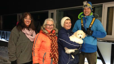 Synnöve Lindholm, Mirja Koponen, Karin Svahnström med hunden Albert i famnen och idrottsinstruktör Heikki Kiili poserar utanför Solvalla Arenan en vintrig kväll i november.