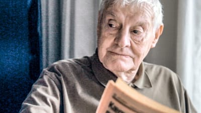 Otto läser tidningen och kastar en blick åt sidan.